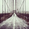 Not many people crossing the Brooklyn Bridge during a snowstorm